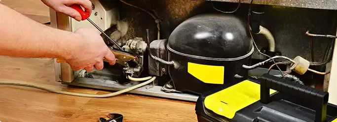 Refrigerator repair technician fixing the compressor and wiring in Pleasant Hill, OR