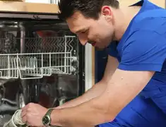 Dishwasher repair technician inspecting and servicing an open dishwasher in Eugene, OR