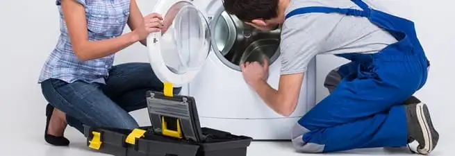 Washer repair technician inspecting a front-load washing machine with tools in Eugene, OR