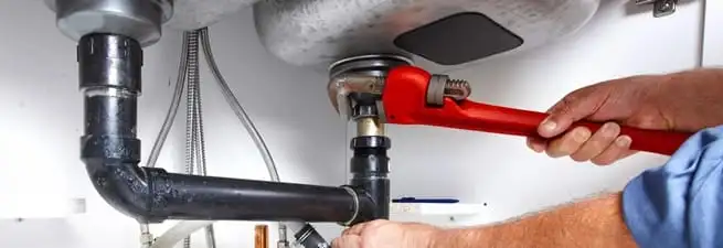 Garbage disposal repair technician tightening the sink drain and disposal connection in Eugene, OR