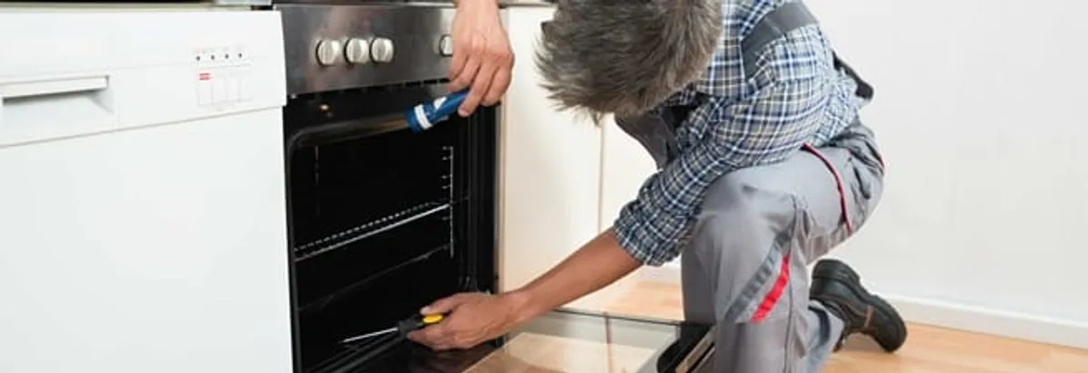Oven repair technician inspecting and servicing an electric oven in Eugene, OR