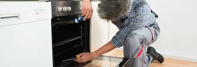 Oven repair technician inspecting and servicing an electric oven in Eugene, OR