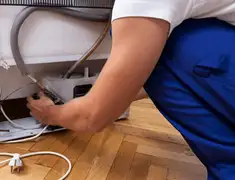Appliance repair technician fixing refrigerator water line and connections in Eugene, OR