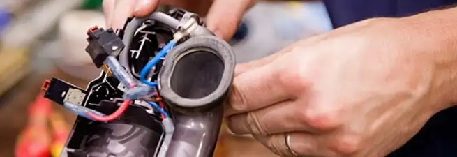 Vacuum repair technician reconnecting wiring and components in Eugene, OR