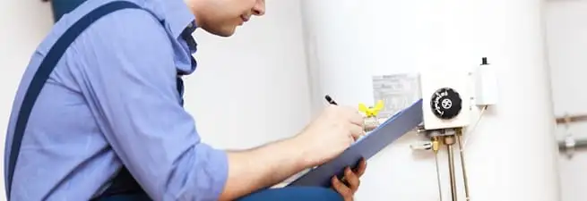Water heater repair technician inspecting the unit and recording service notes in Eugene, OR