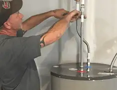 Water heater repair technician tightening supply line connections in Eugene, OR