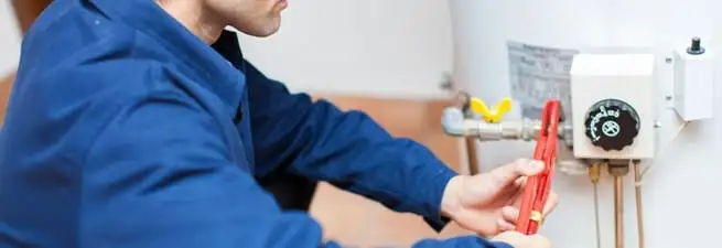 Water heater repair technician adjusting the temperature control and gas valve in Eugene, OR